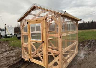 Amish-built greenhouse with polycarbonate panels set in a grass field