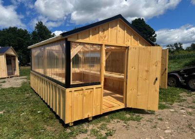 Amish greenhouse with wood plank walls and polycarbonate roof