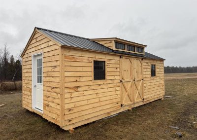 Amish shed with wood siding, black roof and cupola vent