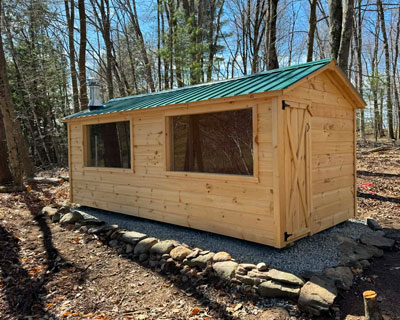 Wood outdoor sauna with a green roof and two large windows